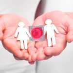 Muñecos de papel con preservativo en las palmas de una persona