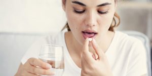 Mujer tomando antiacidos para el dolor de garganta